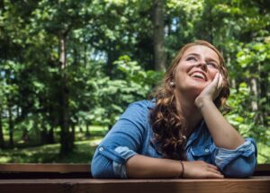 Smiling young woman near forest