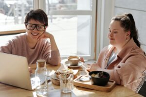 young woman with Down syndrome and friend eating at table